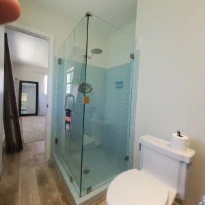 Shower glass enclosure with sleek design and blue tiled walls in bathroom.