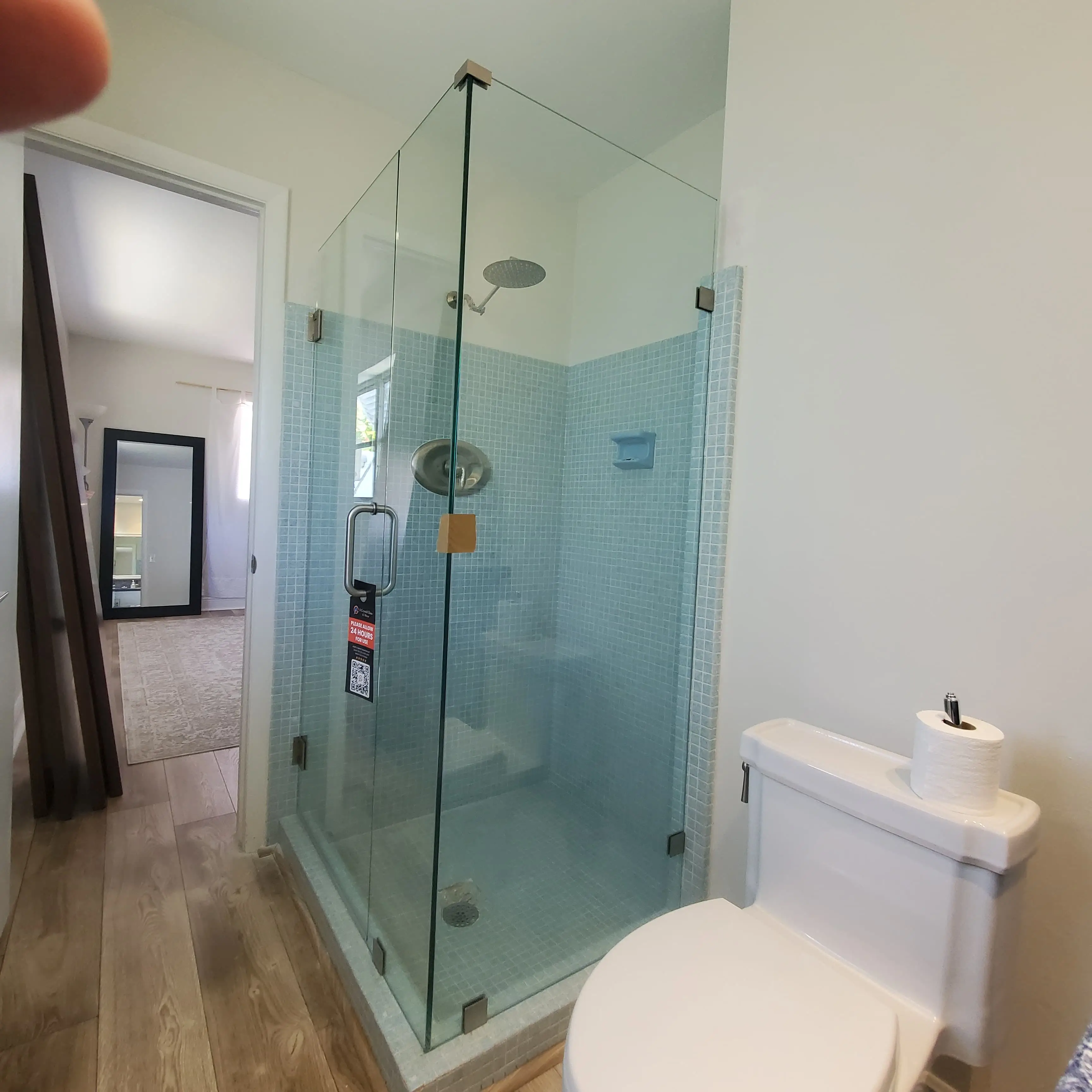 Shower glass enclosure with sleek design and blue tiled walls in bathroom.