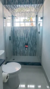 Safe, modern glass bathroom shower with textured panels and large window.