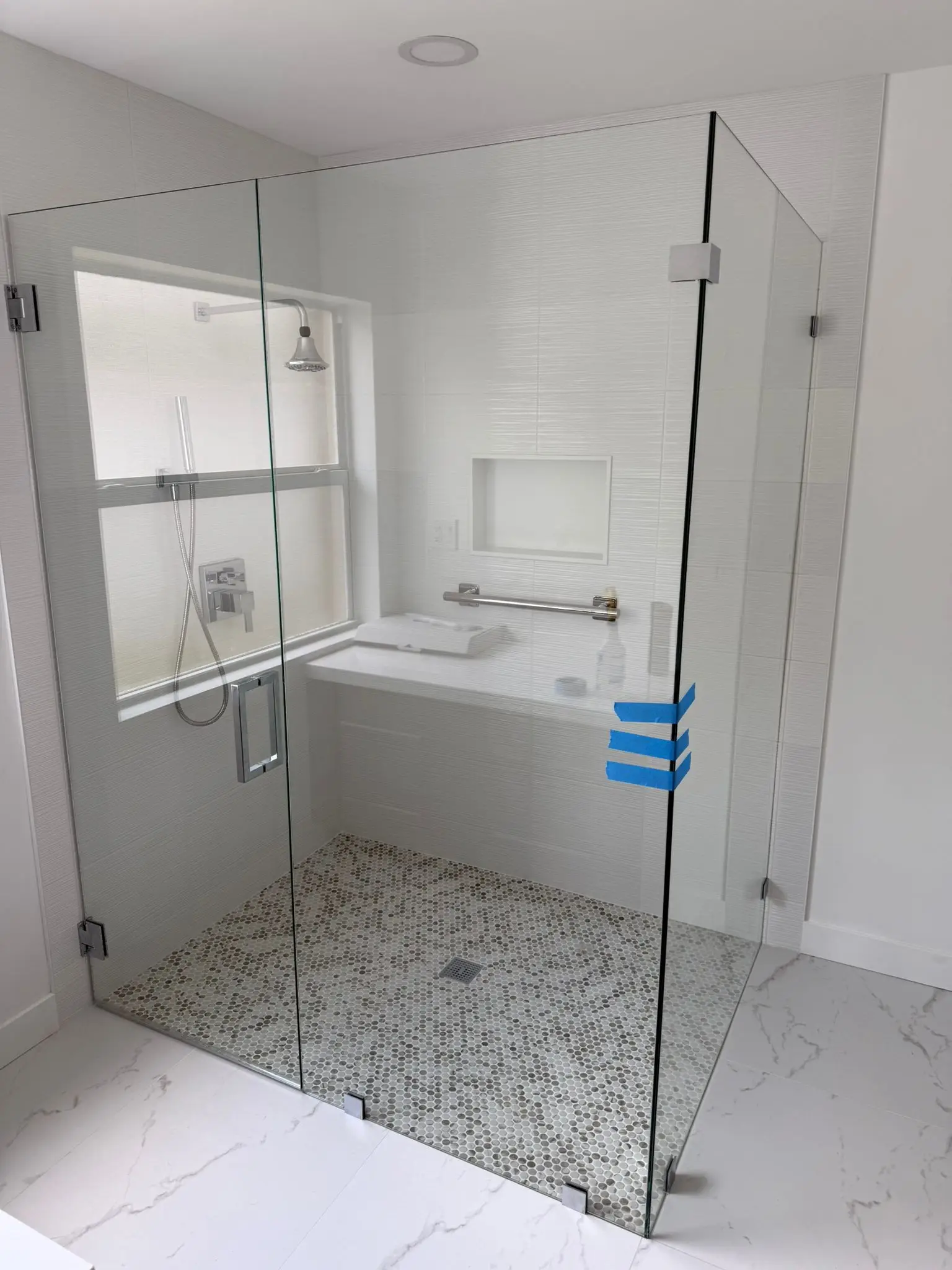 Clear glass shower door with sleek hinges, frameless design, and pebble floor tiles for luxury bathroom appeal.