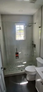 Bright bathroom featuring a sleek glass shower with a window for natural light and contemporary fixtures.
