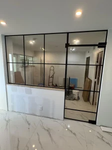 Modern glass wall with black metal frame for stylish interior separation.