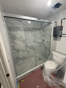 High-quality glass shower door with marble tiles, modern bathroom design.