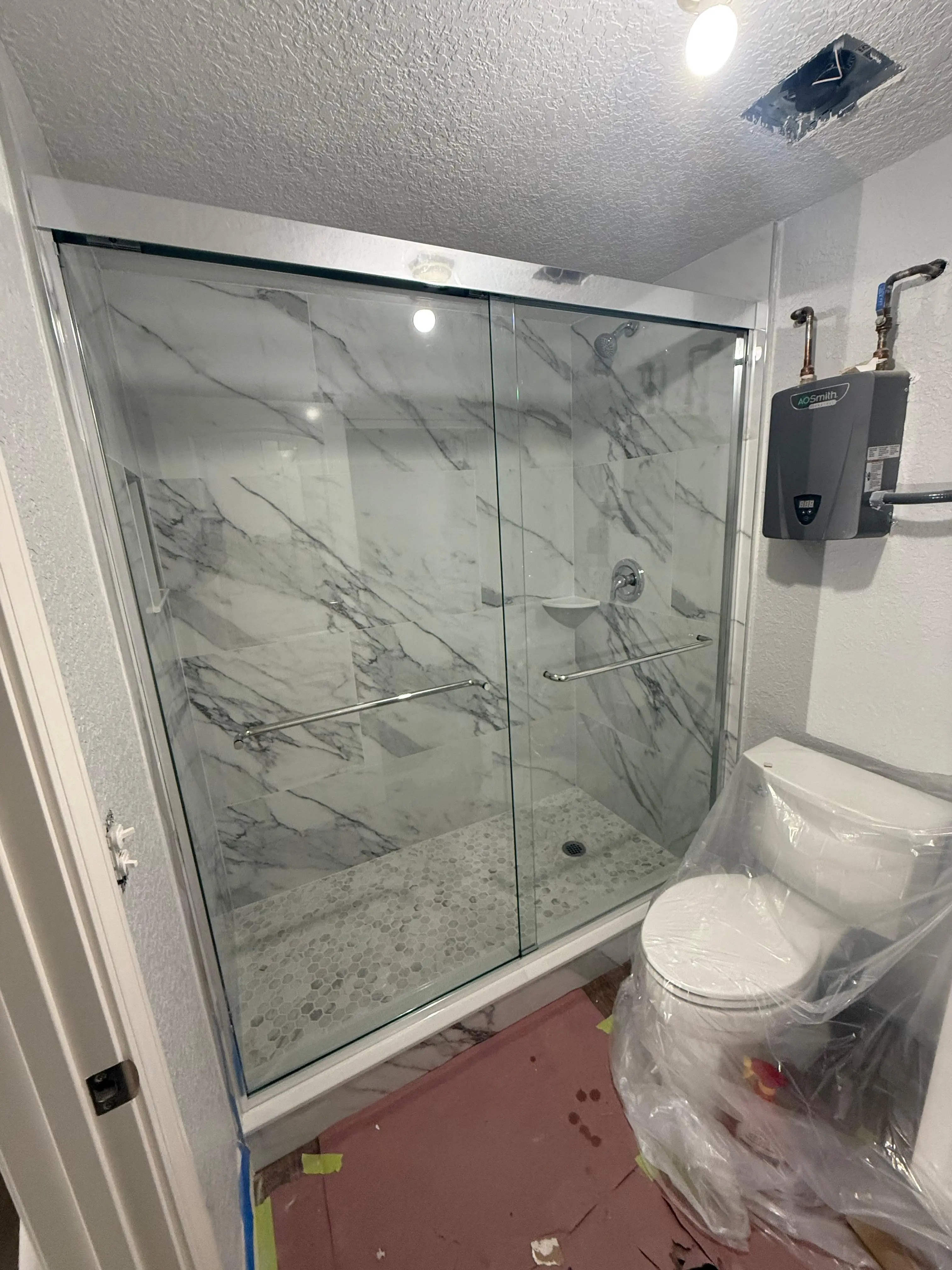 High-quality glass shower door with marble tiles, modern bathroom design.