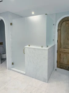 Clear glass shower with brass handle, modern bathroom design, high-quality glass, elegant fixtures.