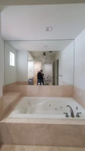 Mirror wall in bathroom with Jacuzzi tub.