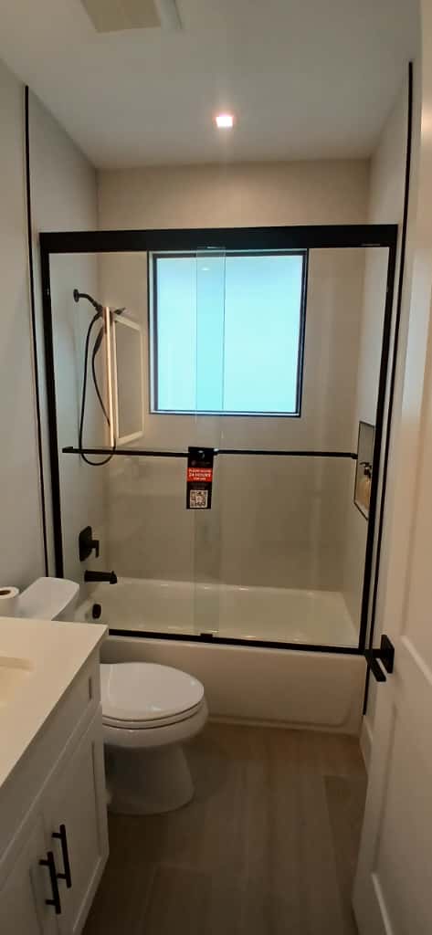 Clear glass shower door with black frame and hardware.