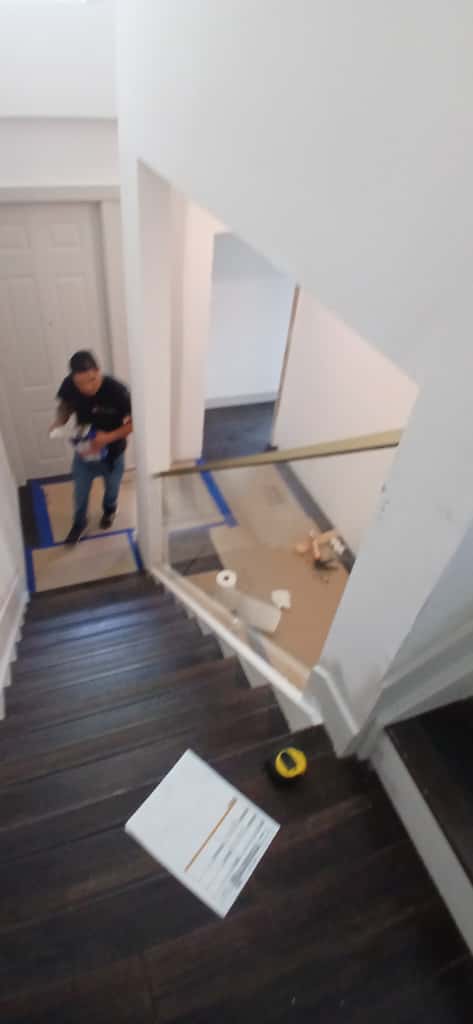 Wide view of glass railing being installed at staircase.