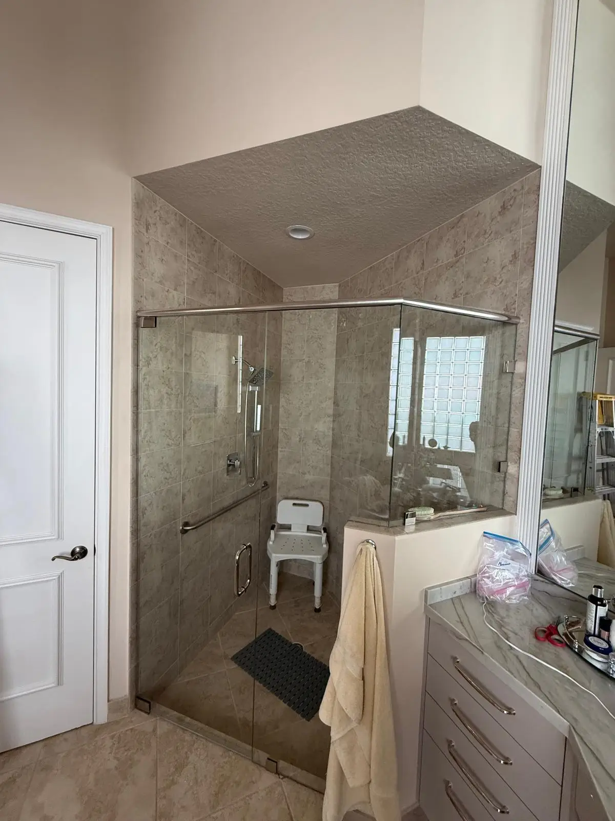 Bright, modern bathroom with custom glass shower door and marble accents.