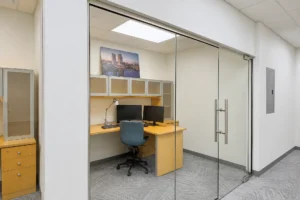 Private office behind a frameless glass front at Related Ross in West Palm Beach